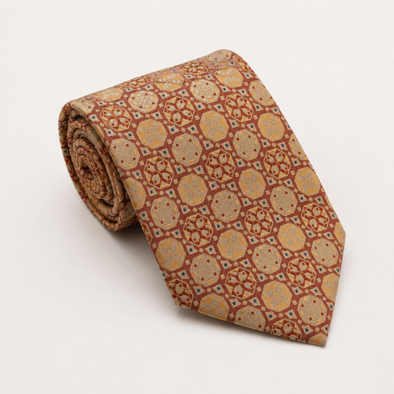A rolled George Neale burnt orange and gold patterned silk tie.