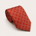 A rolled George Neale red and gold patterned silk tie.