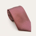A rolled George Neale red and cream patterned silk tie.