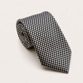 A rolled George Neale black and cream patterned silk tie.