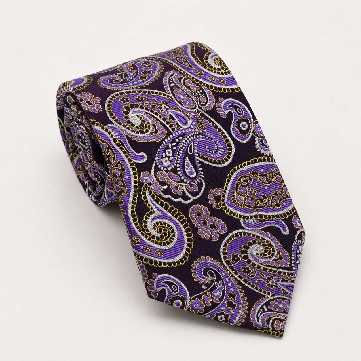 A rolled George Neale purple and gold paisley silk tie.
