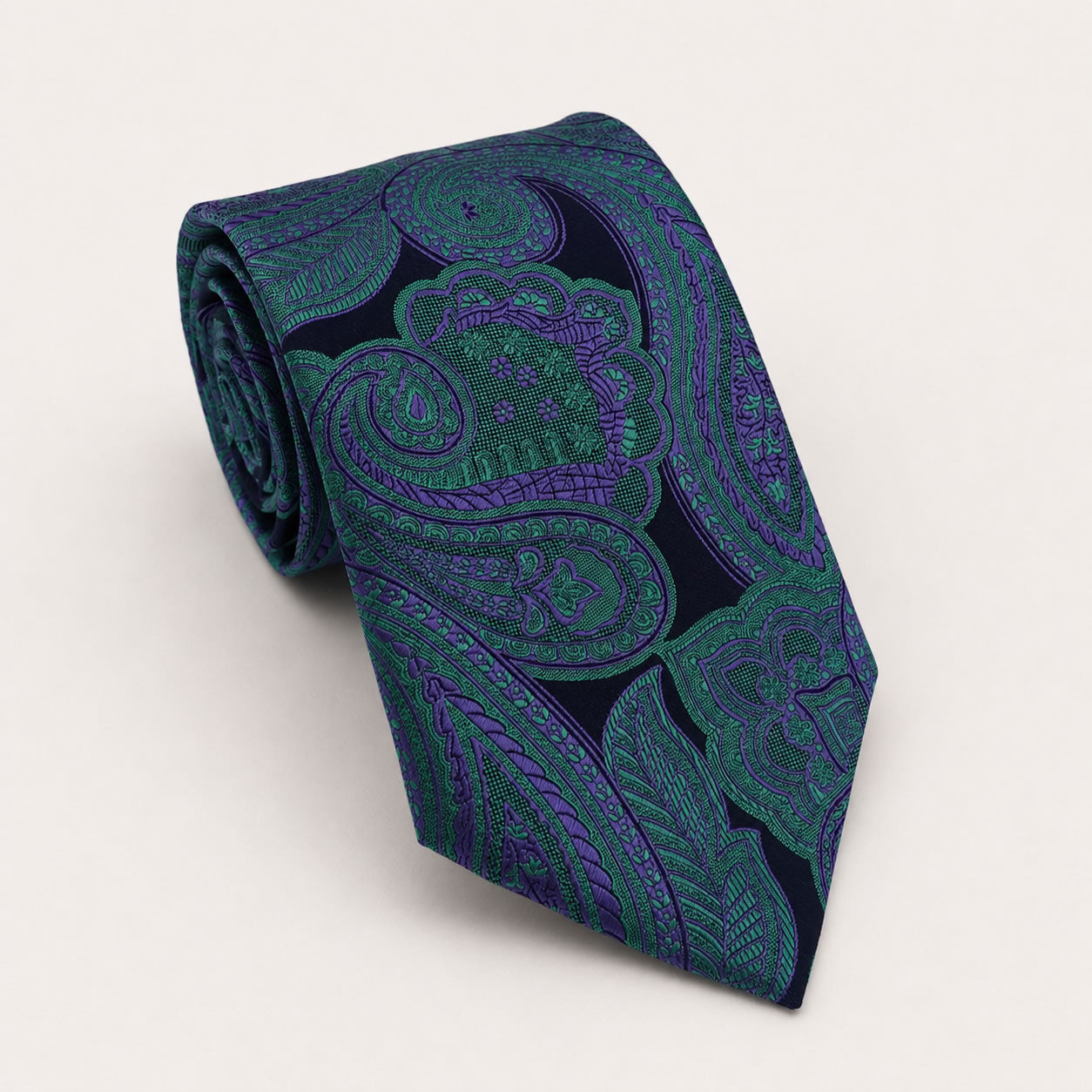 A rolled George Neale dark blue and green paisley silk tie.