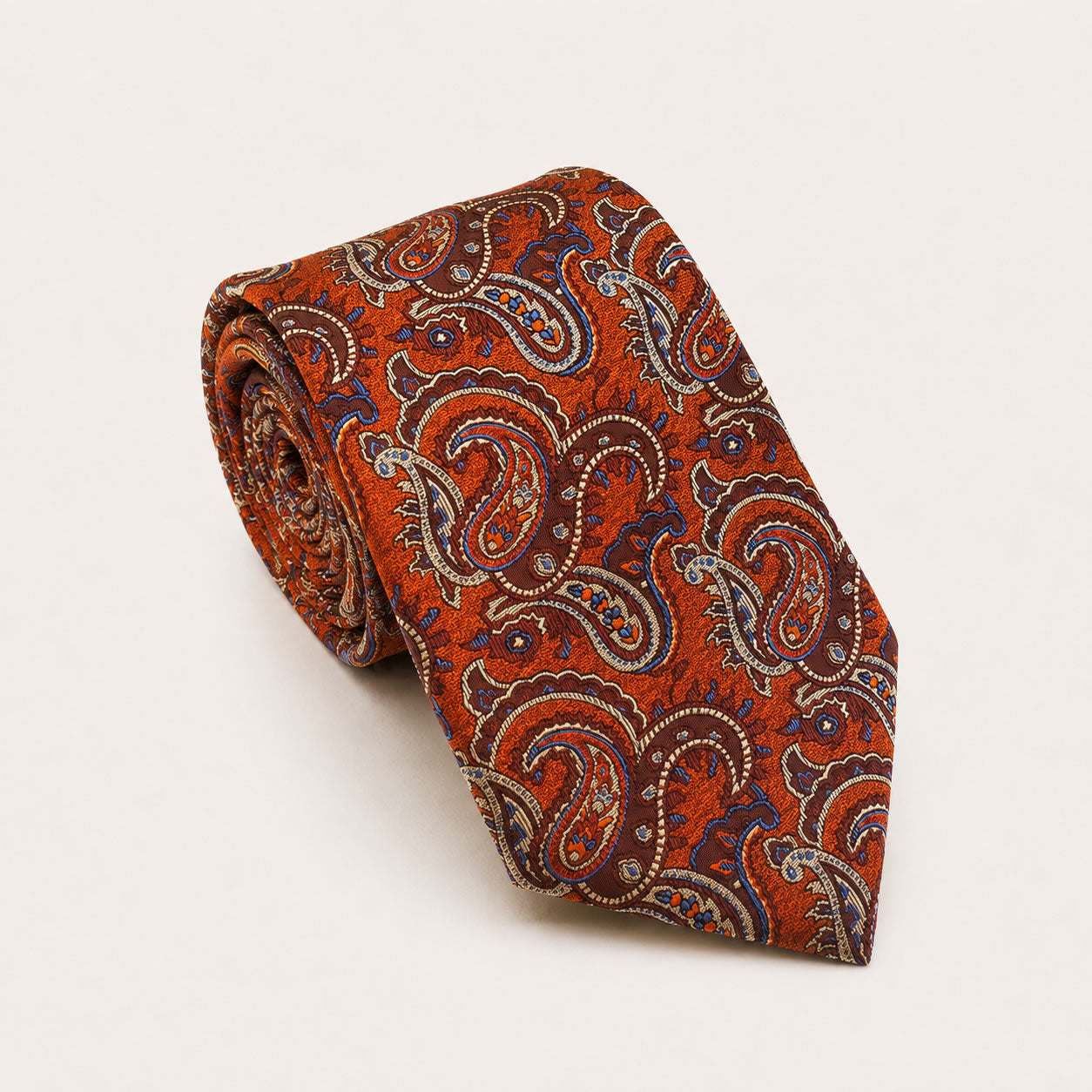 A rolled George Neale burnt orange and blue paisley silk tie.