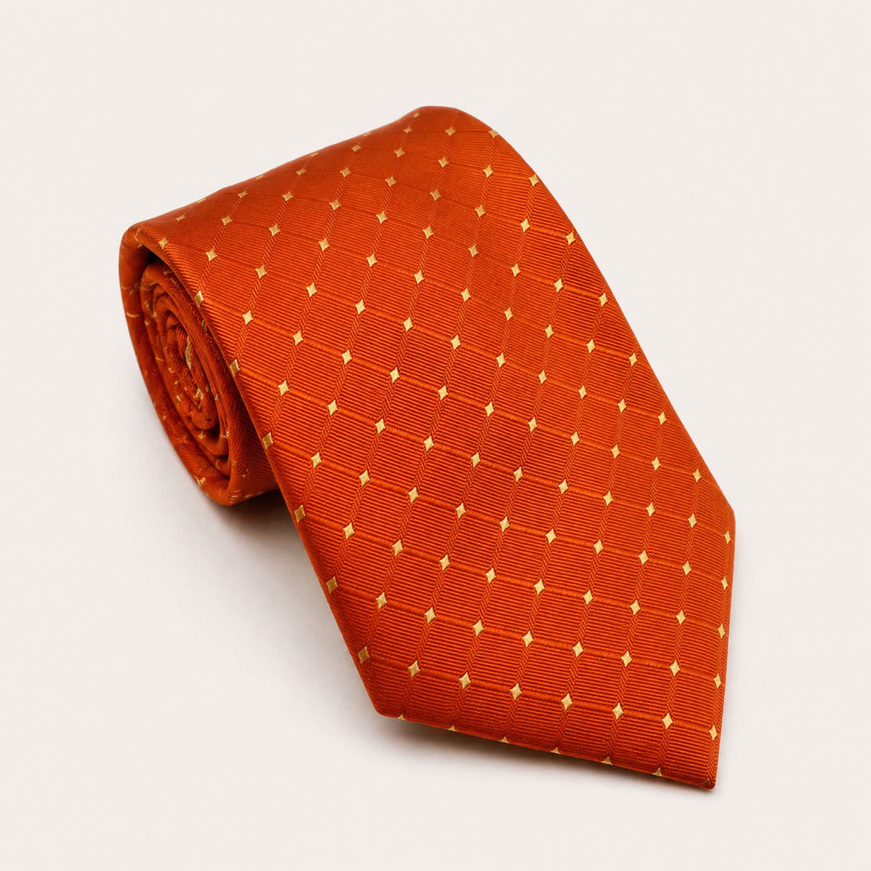 A rolled George Neale orange and gold polka dot silk tie.
