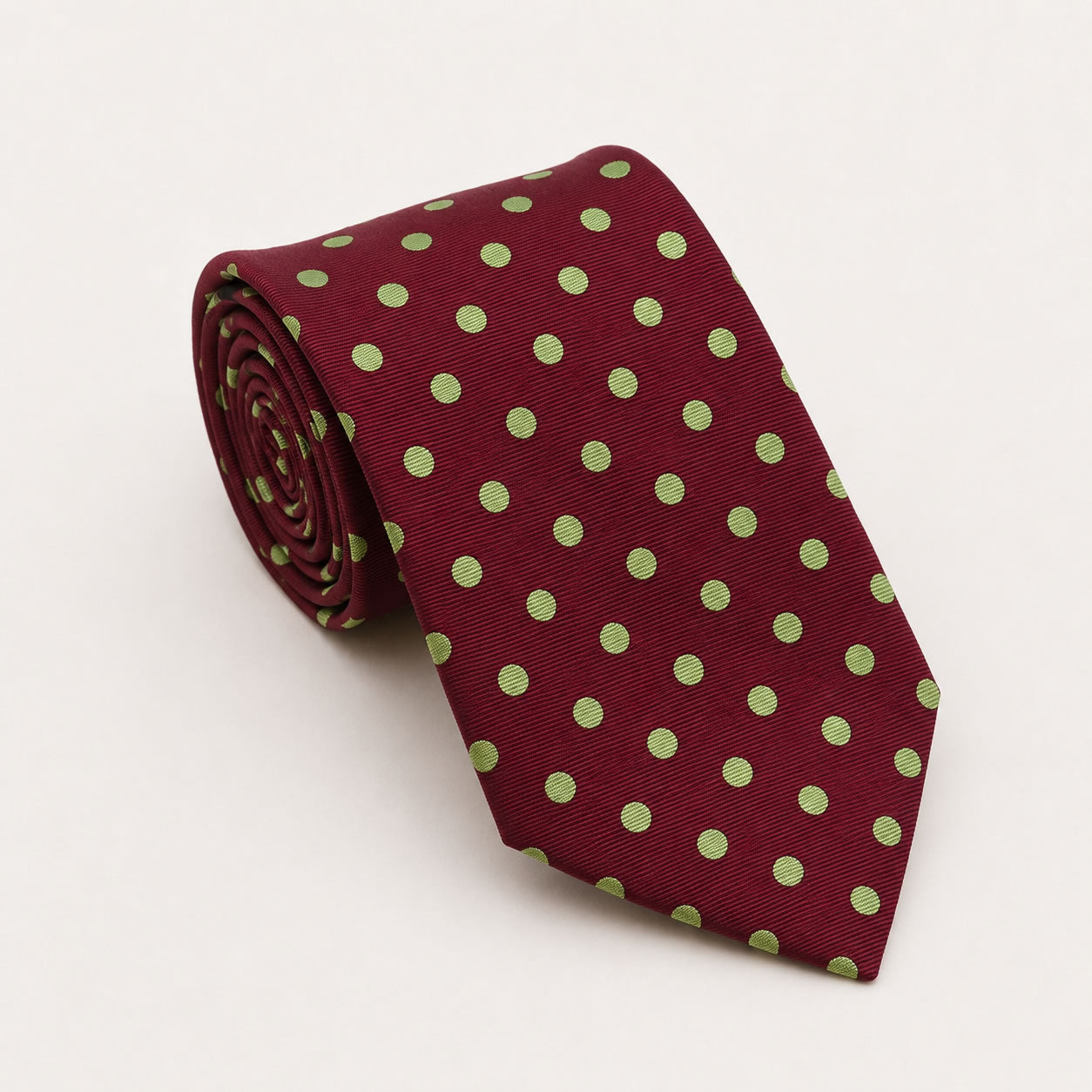 A rolled George Neale burgundy and green polka dot silk tie.