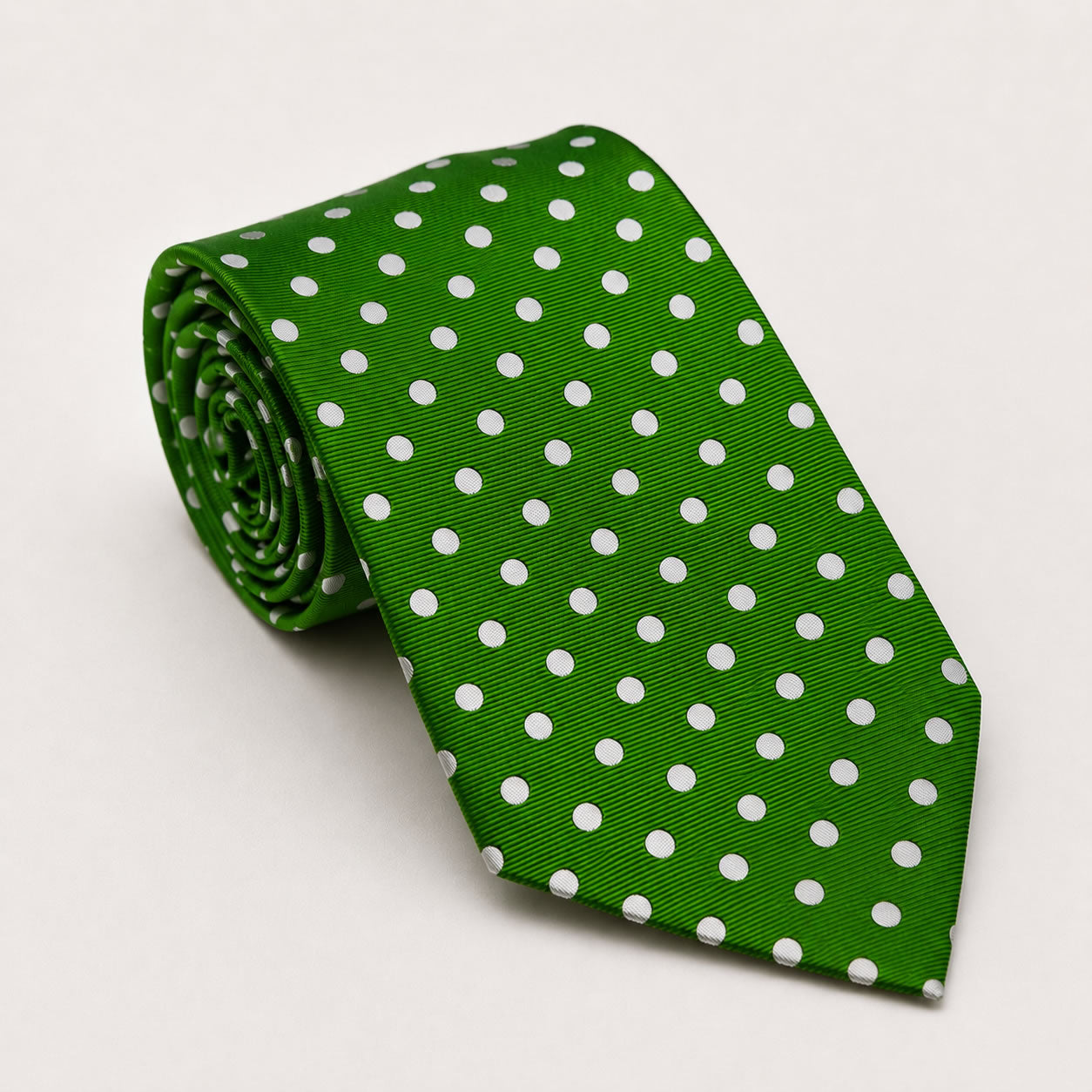 A rolled George Neale green and white polka dot silk tie.