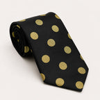 A rolled George Neale black and gold polka dot silk tie.