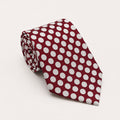 A rolled George Neale burgundy and white polka dot silk tie.