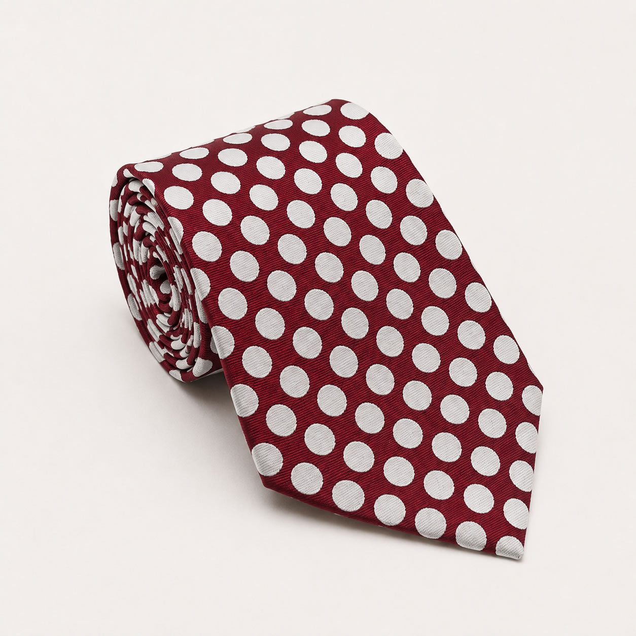 A rolled George Neale burgundy and white polka dot silk tie.