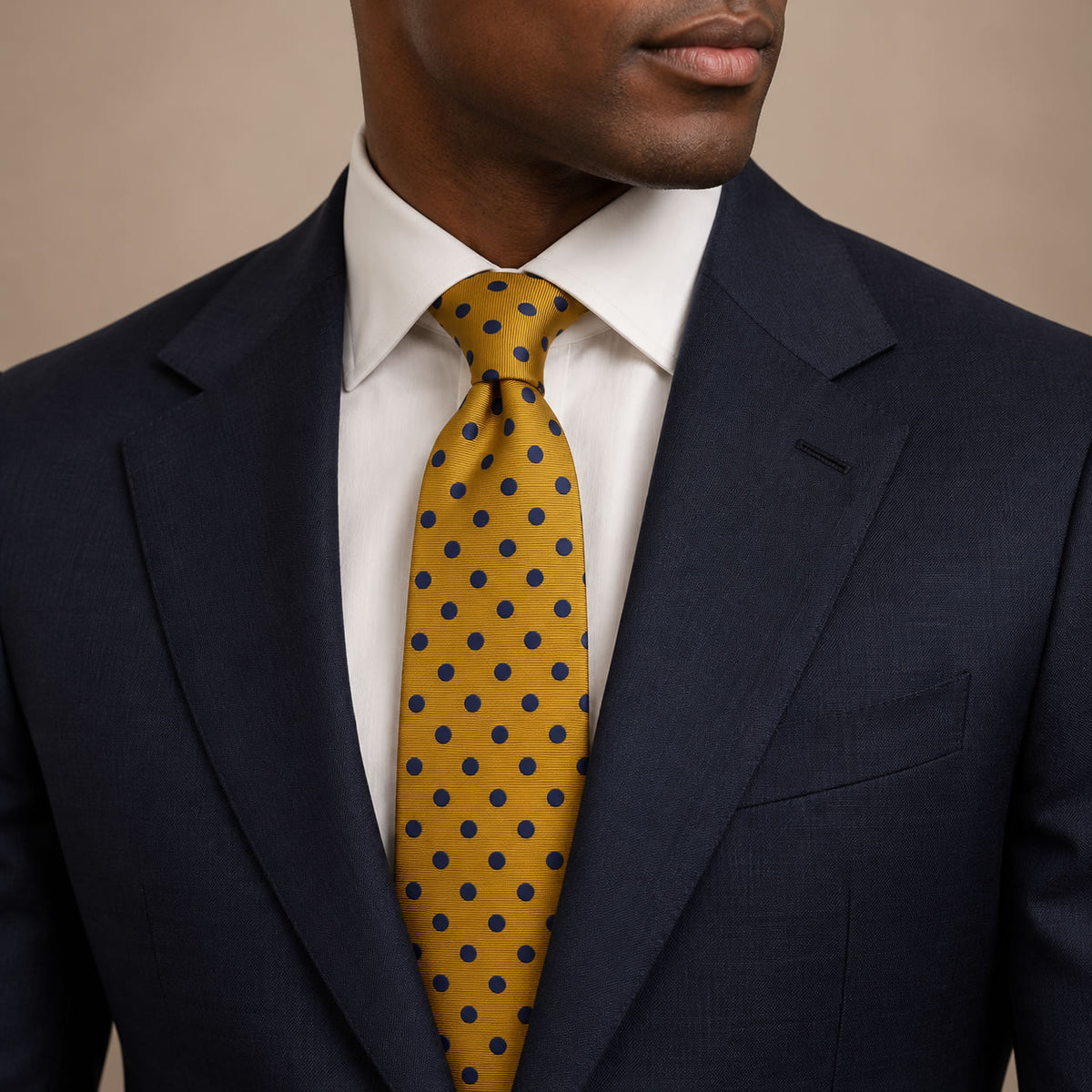 Gold and Navy Polka Dot Silk Tie by George Neale, worn by a model with a suit and shirt