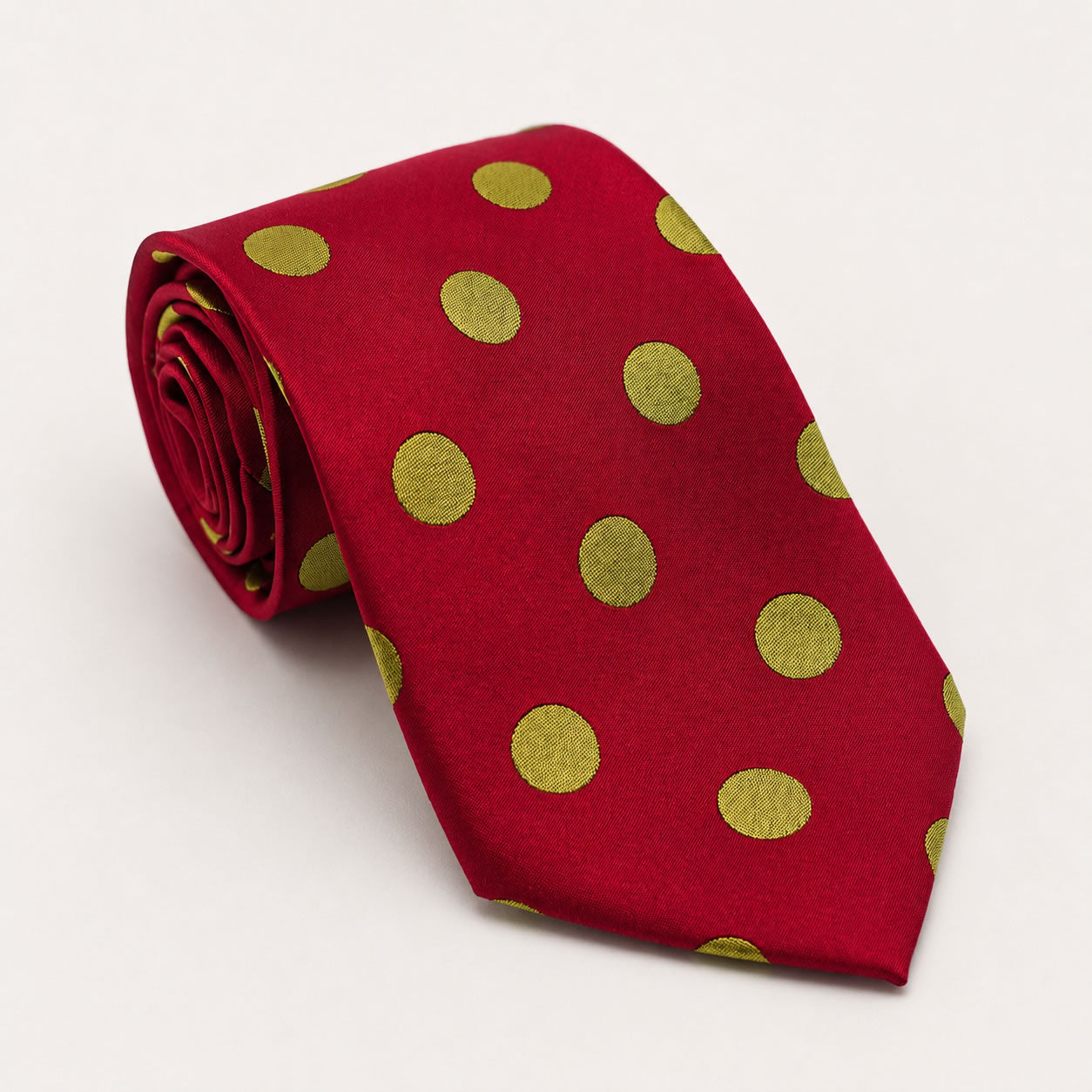 A rolled George Neale red and gold polka dot silk tie.