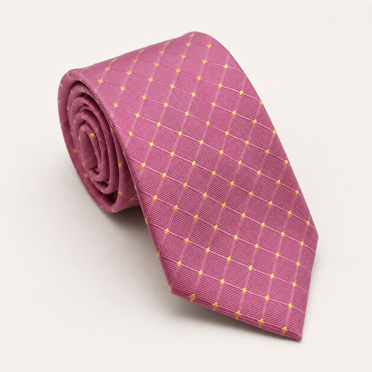 A rolled George Neale pink and gold polka dot silk tie.
