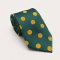 A rolled George Neale forest green and gold polka dot silk tie.