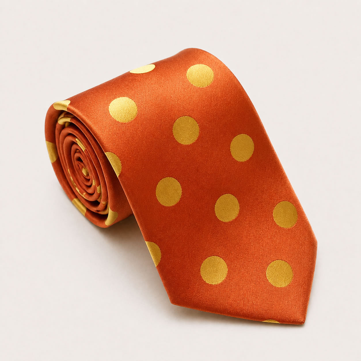 A rolled George Neale orange and gold polka dot silk tie.
