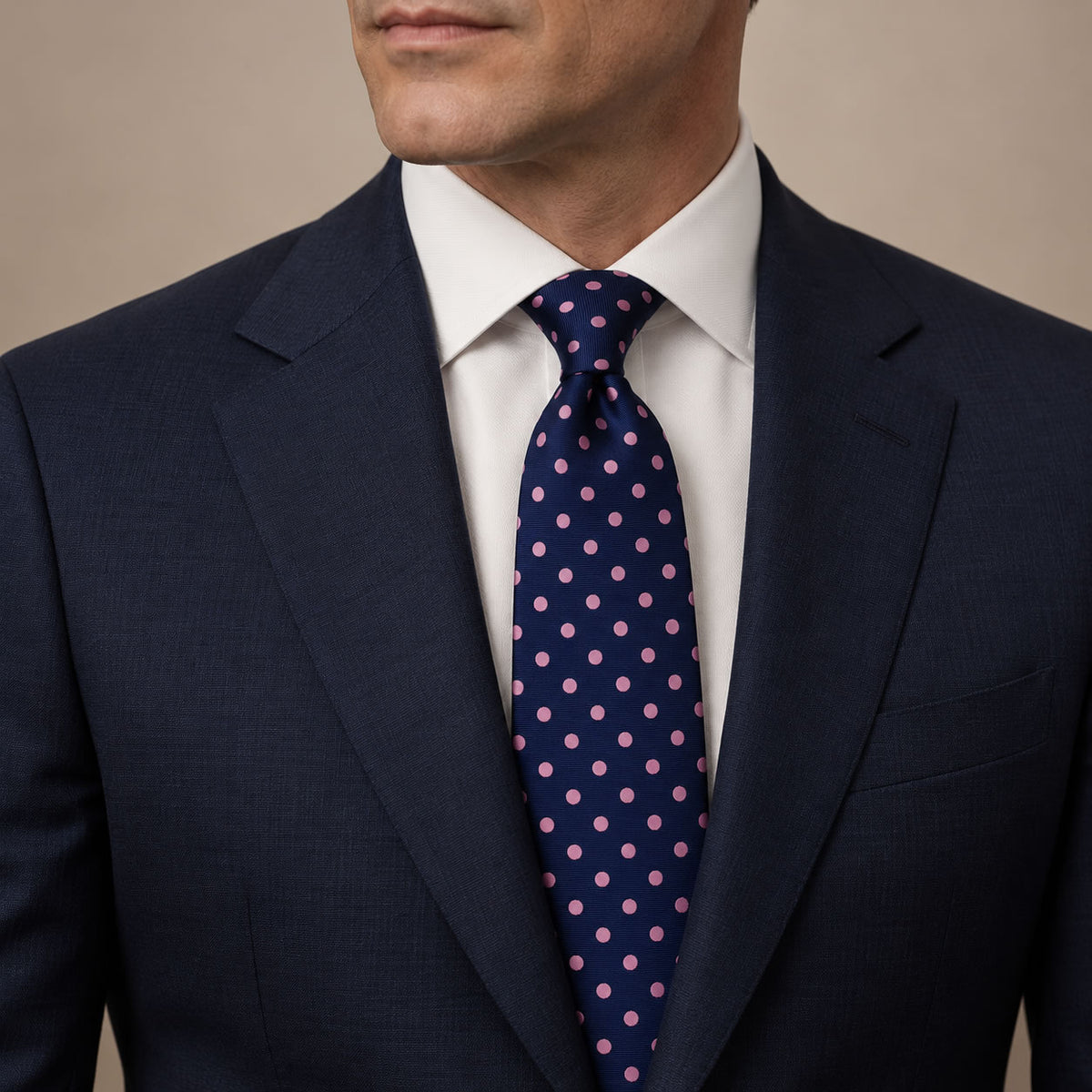 Navy and Pink Polka Dot Silk Tie by George Neale, worn by a model with a suit and shirt