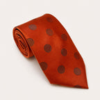 A rolled George Neale burnt orange polka dot silk tie.